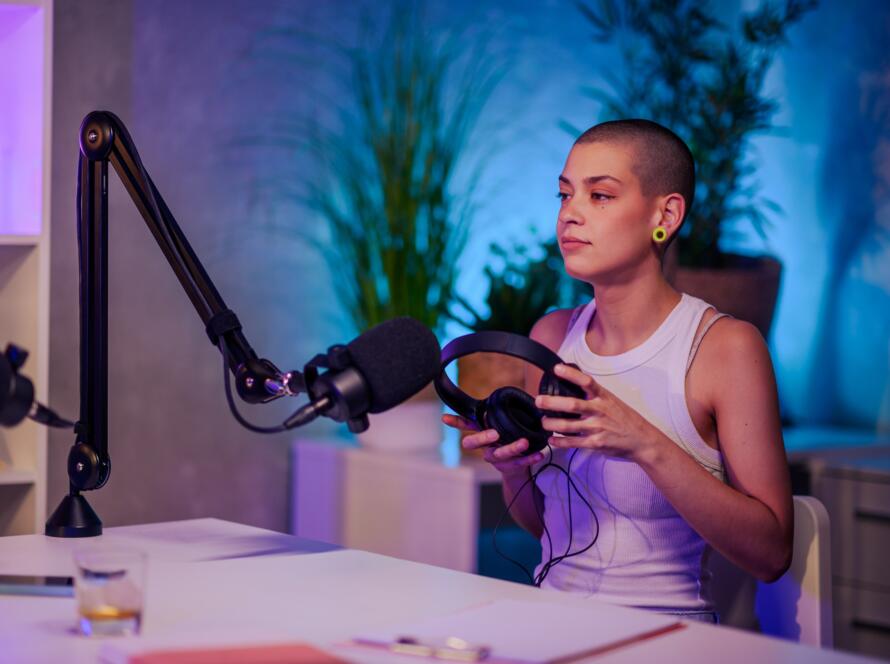 Urban girl is sitting in a home recording studio nd preparing for recording a podcast.