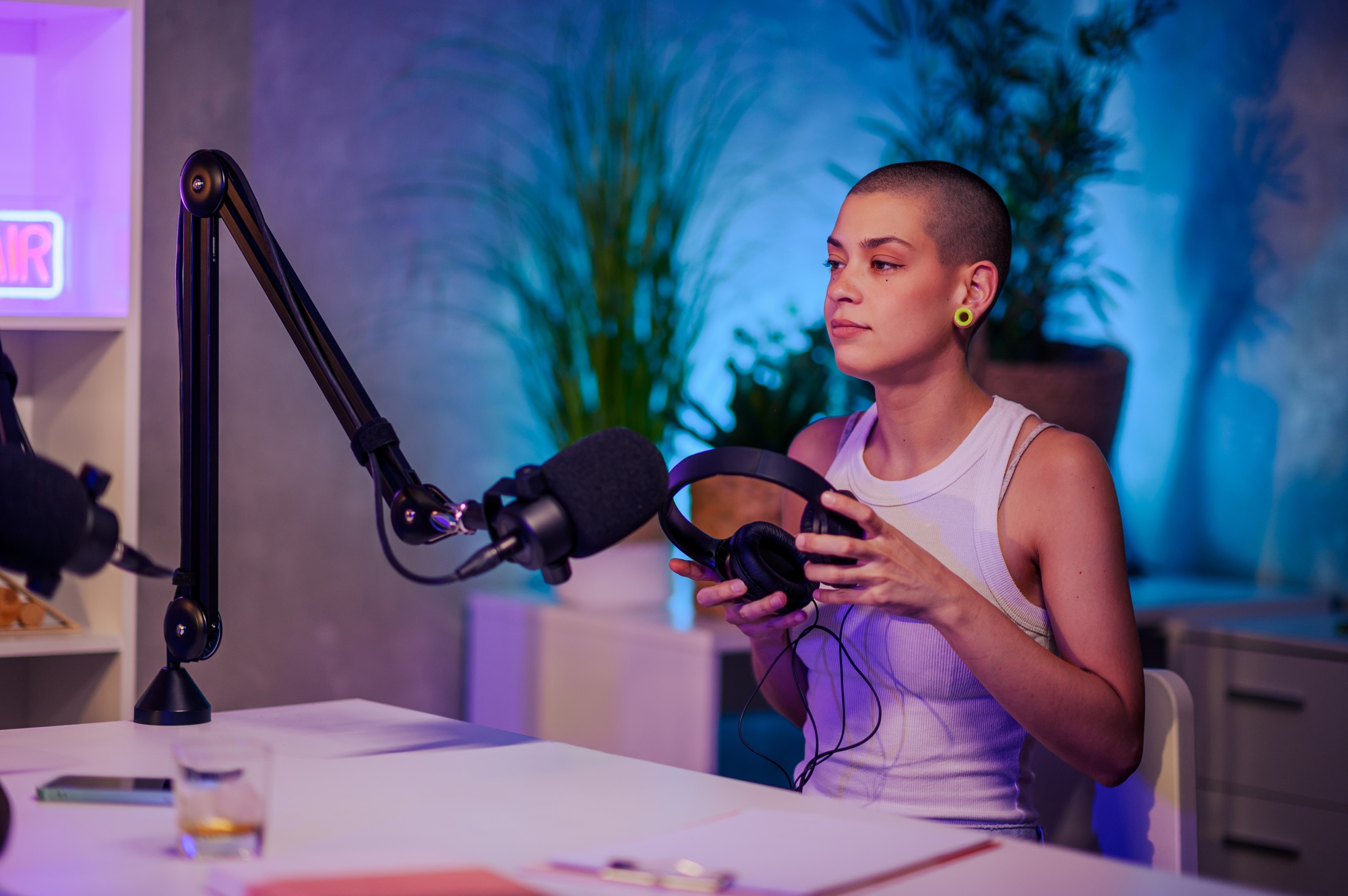 Urban girl is sitting in a home recording studio nd preparing for recording a podcast.